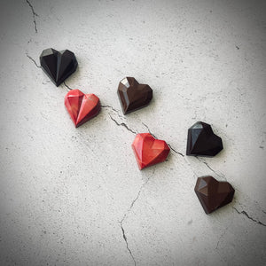 Six chocolats artisanaux rouges et bruns en forme de cœur, comprenant 2 cœurs caramel, 2 cœurs praliné maison, et 2 cœurs gelée d’airelle et praliné amandes. Parfaits pour des cadeaux de Saint-valentin gourmands fabriqués à Montréal.