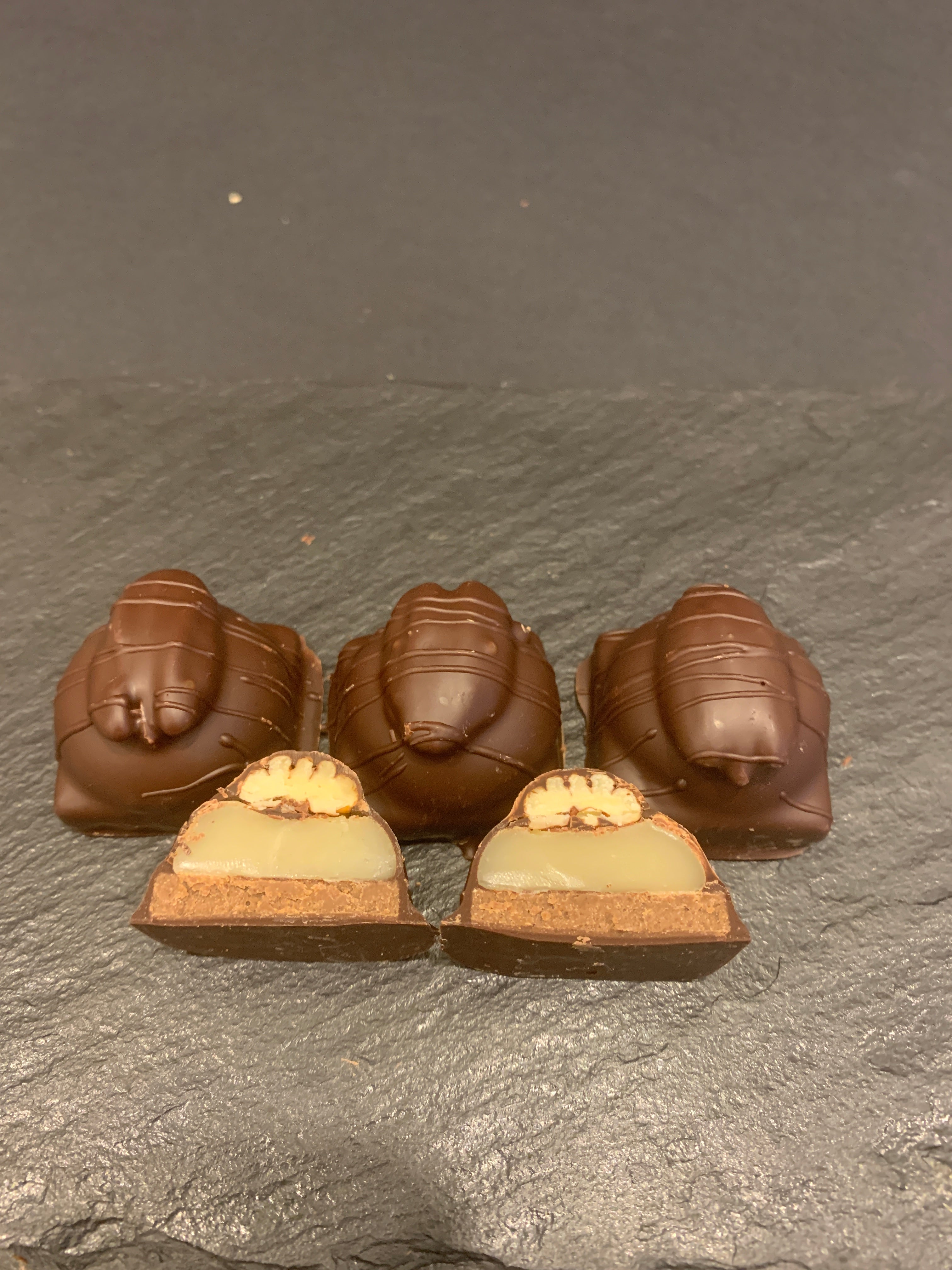 Bouchées tortues, enrobées de chocolat noir ou lait, faites de caramel tendre, praliné à la pacane rôtie et pacane entière sur le dessus.